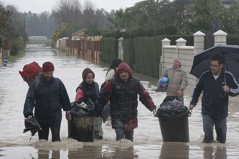 Un grupo de gente deambula por una zona inundada de Fontanar de Quintos en Córdoba, tras las lluvias de las últimas semanas que han forzado el desalojo de sus viviendas.