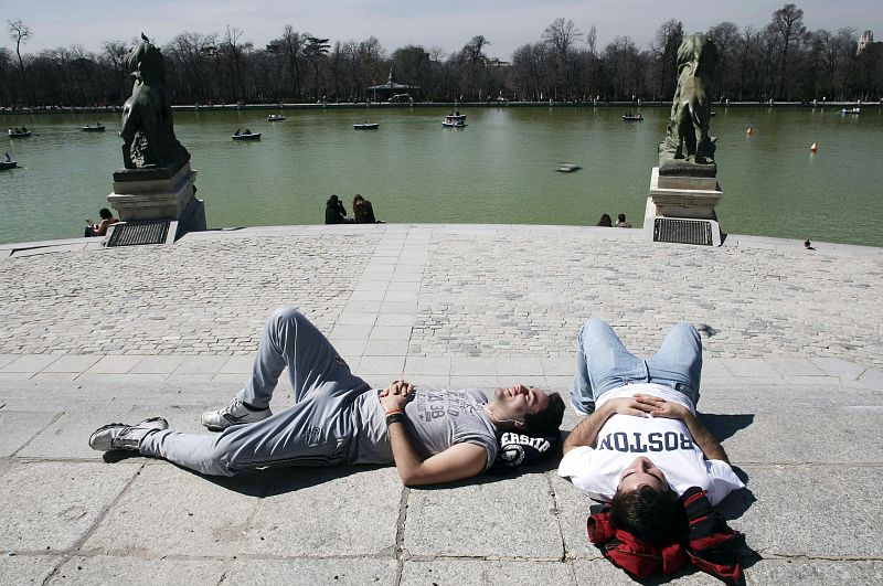 People lie in the sun at Madrid's Retiro Park on a warm morning just a few days before the start of spring