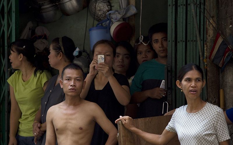 Residents stand near the gates to their shops after clashes between army soldiers and anti-government 'red shirt' supporters near Bangkok's Din Daeng intersection