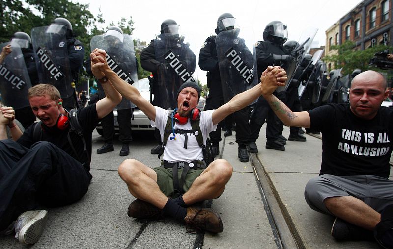 Los manifestantes se sientan en el suelo frente a los agentes de policía en las protestas contra el G-20