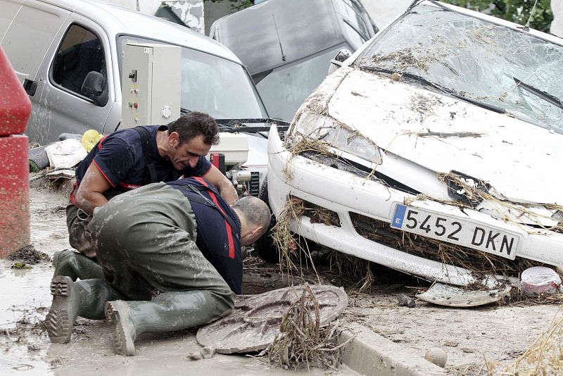 Dos bomberos trabajan en el alcantarillado de una calle de la localidad de Aguilar de la Frontera, Córdoba.