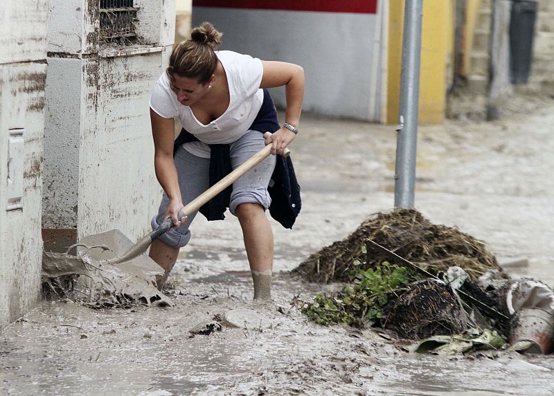 Una mujer de la localidad de Aguilar de la Frontera limpia la puerta de su casa.