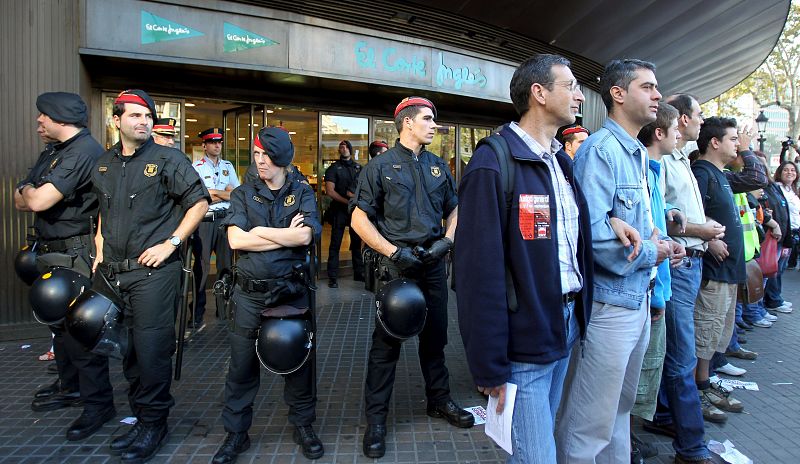 Un piquete custodiado por los mossos d'esquadra ante la puerta de unos grandes almacenes, durante la jornada de huelga general en Barcelona.