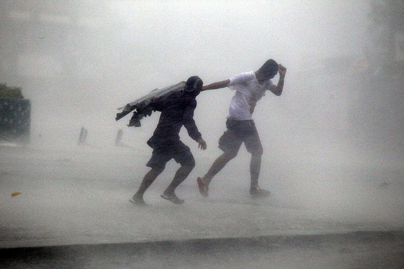Dos personas luchan contra la fuerza del viento y la lluvia, en la provincia de Isabela (en el norte de Filipinas)