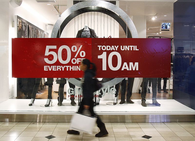 Woman walks by a store's discount advertisement inside the Roosevelt Field Mall in Garden City, New York