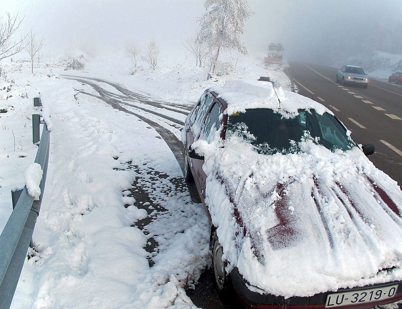 Un coche, cubierto de nieve en la carretera N-640, de Monterroso a Lugo.