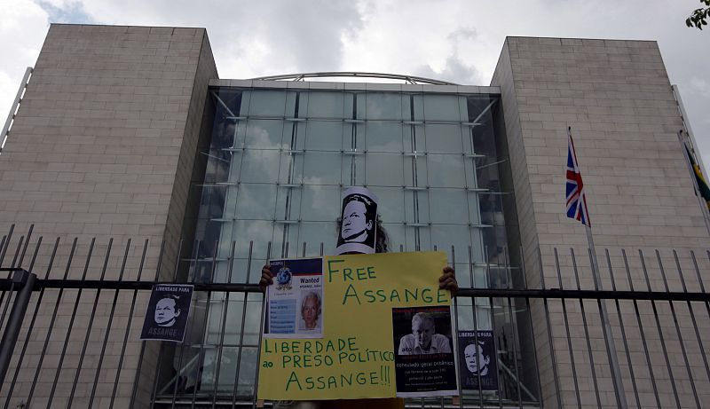 Protester holds pictures and a sign in support of the WikiLeaks founder Julian Assange during a demonstration in front of the British Consulate in Sao Paulo