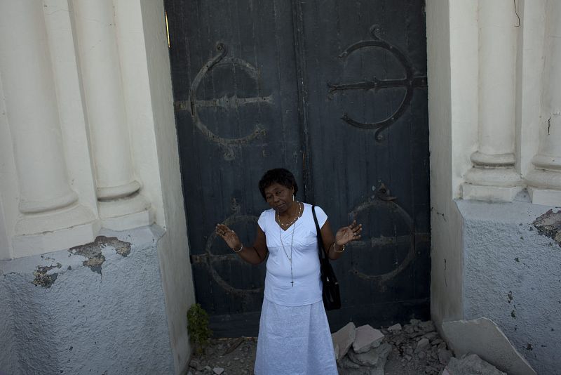 Una mujer reza en frente de la puerta de la catedral de Puerto Príncipe.