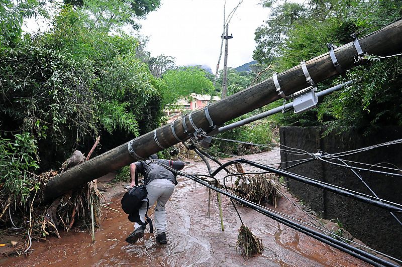Un hombre cruza debajo de un poste que cayó sobre una carretera en Teresópolis tras las fuertes lluvias.