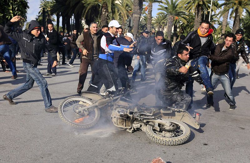 Un grupo de manifestantes dan patadas a un policía durante los enfrentamientos en la capital tunecina
