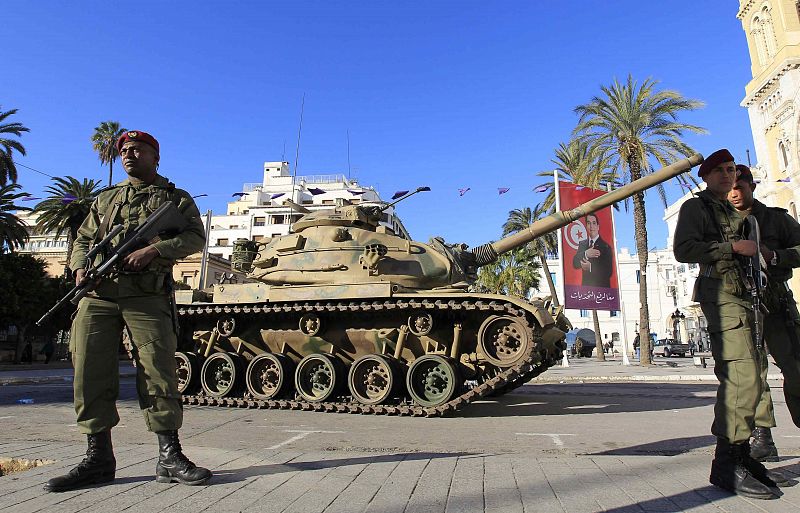 Tunisian army soldiers stand guard near a tank in downtown Tunis