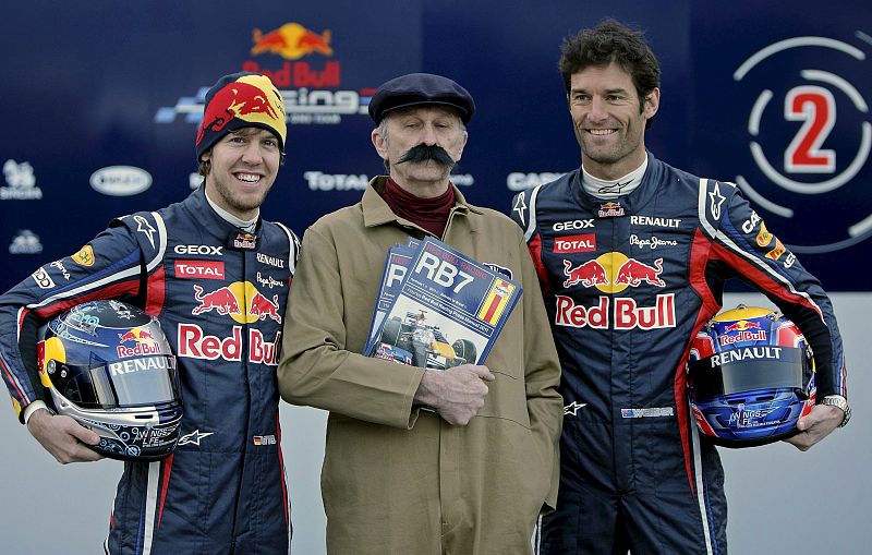 Los pilotos del equipo Red Bull de Fórmula Uno, el campeón del Mundo el alemán Sebastian Vettel, y el australiano Mark Webber, posan con un figurante disfrazdo de mecánico de principios del siglo XX.