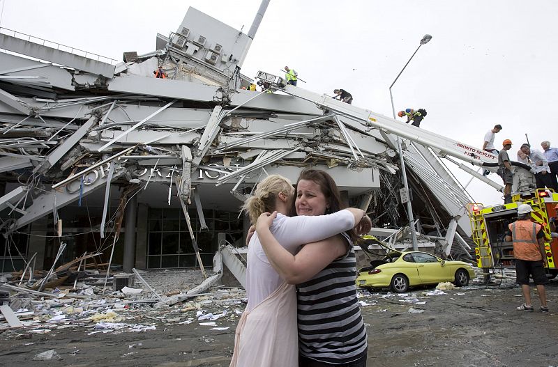 Dos mujeres se abrazan entre lágrimas frente a uno de los edificios que se han caído por el seísmo