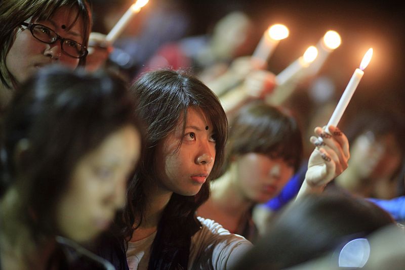 A member of the volunteer organization, Green Belt Trust, holds a candle to pay tribute to the victims of Japan's earthquake and tsunami during a vigil at the campus of the University of Dhaka