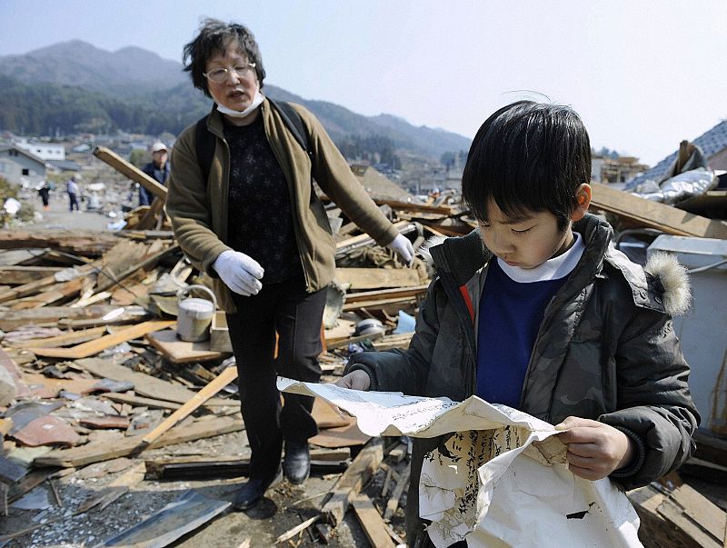 A boy looks at an award certificate he found among debris in Ofunato City, Iwate Prefecture in northern Japan