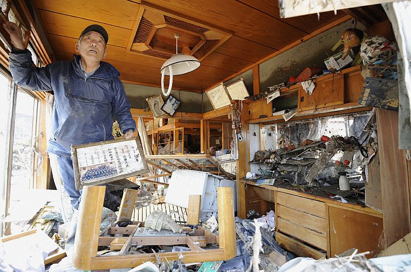 A man cleans up his destroyed home after a magnitude 8.9 earthquake and tsunami hit Minami Sanriku City, Miyagi Prefecture