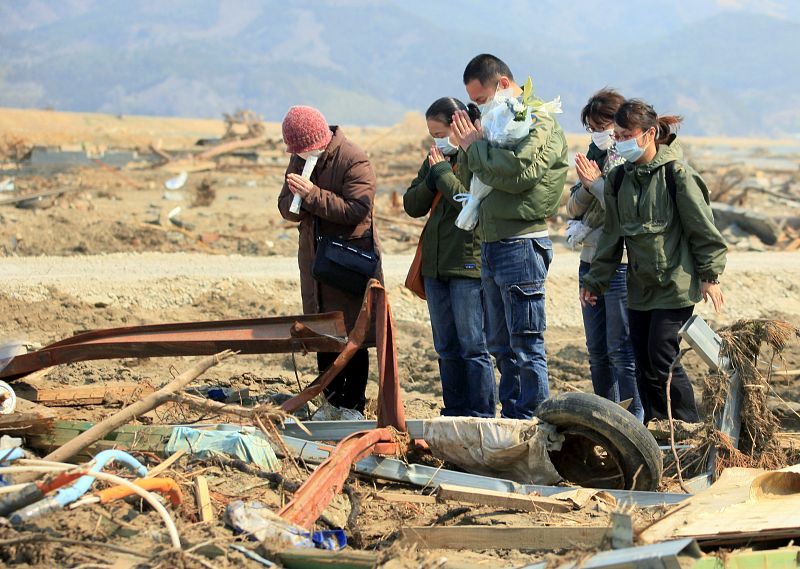 Familiares de una víctima del tsunami rezan en el lugar donde un alumno de la escuela primaria Otawa fue encontrado muerto, a unos 50 metros de la escuela, hoy, miércoles 13 de abril de 2011 en Ishinomaki, prefectura de Miyagi (Japón)