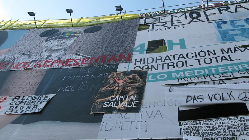 Este muestrario de carteles que hay en este edificio, entre las calle del Carmen y Preciados, se ha quedado como "un símbolo", explica Pedro, uno de los 'indignados'.