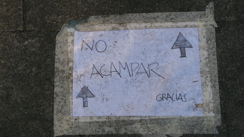 Con estos carteles en el suelo los acampados pretenden que los comerciantes no se vean afectados por la presencia de tiendas de campaña en la puerta de sus negocios.