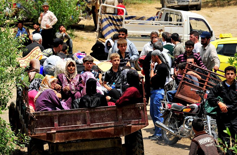 Un grupo de refugiados se apila en un vehículo rumbo a la frontera turca.