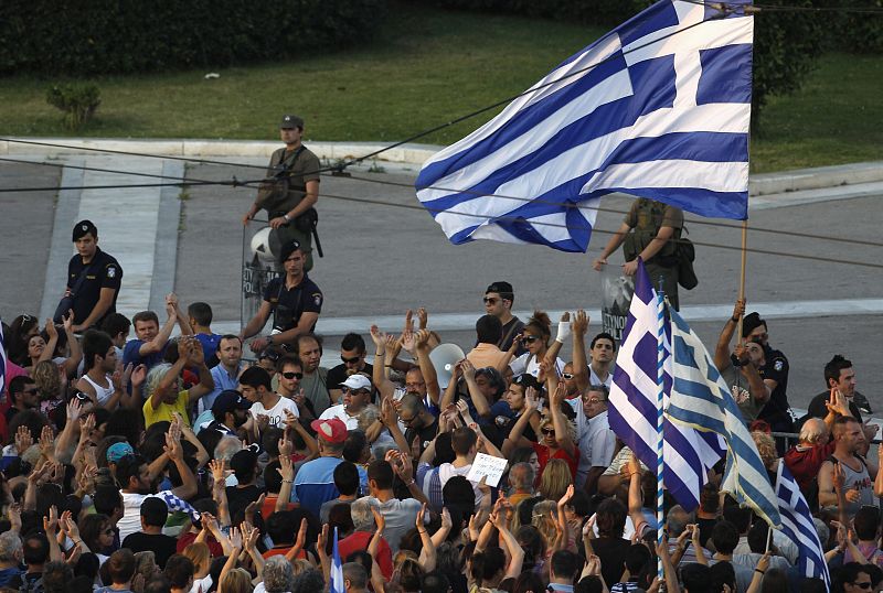 Los manifestantes en la plaza Syntagma portan banderas ante la vigilancia de la policía.