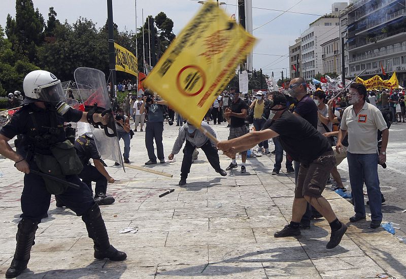 Los manifestanes blanden sus pancartas hacia la policía antidisturbios griega, durante la segunda jornada de protestas