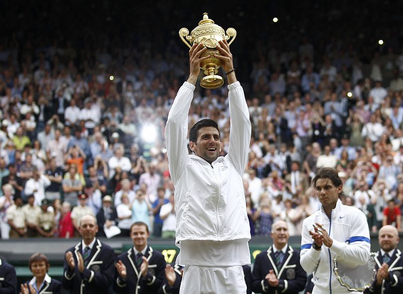 Djokovic levanta el trofeo que le acredita como campeón de Wimbledon ante la mirada de Nadal