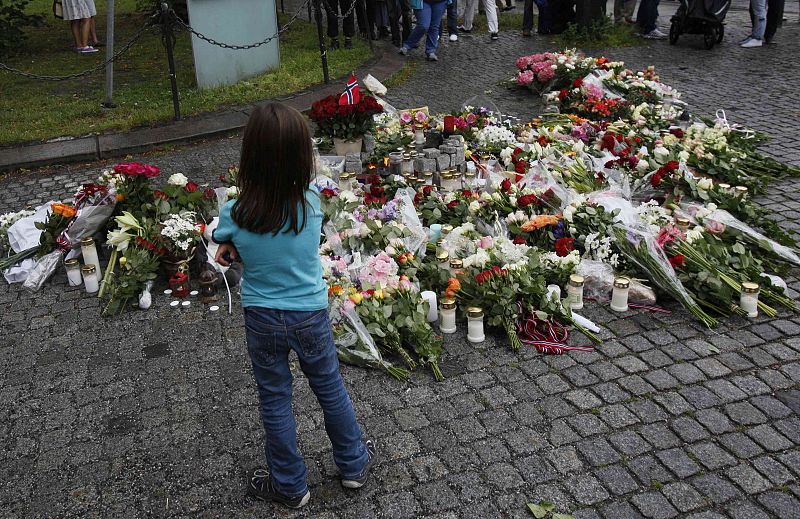 A child looks at flowers and candles that were placed on the market square outside the Oslo cathedral,  to mourn the victims of a bomb blast and a rampage