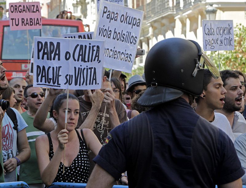 Algunos de los carteles del Movimiento 15M tienen lemas en contra de la visita del papa