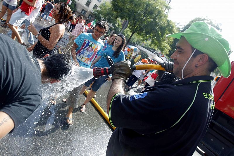 Un miembros del cuerpo de bomberos refresca a un joven esta tarde en la plaza de Cibeles