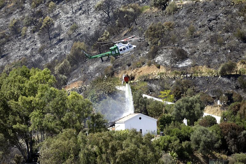 Un helicóptero suelta agua sobre una de las viviendas que habian sido desaloladas