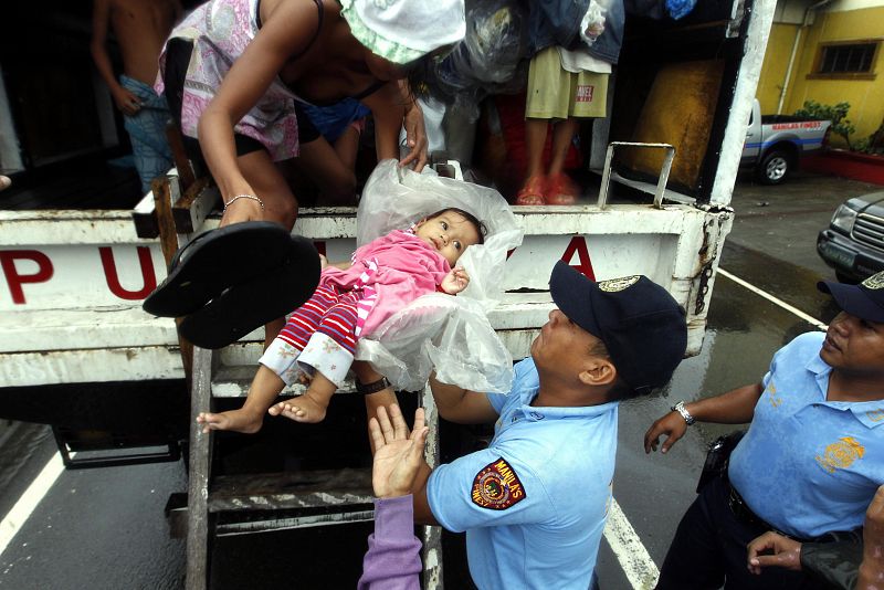 Un policía asistiendo a un bebe durante la evacuación de un barrio marginal de Manila