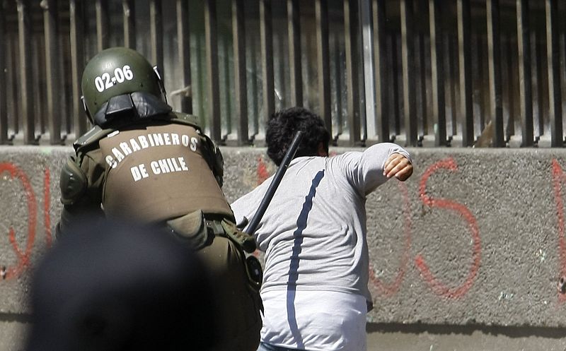 Un miembro de la policía antidisturbios golpea a un manifestante en Chile