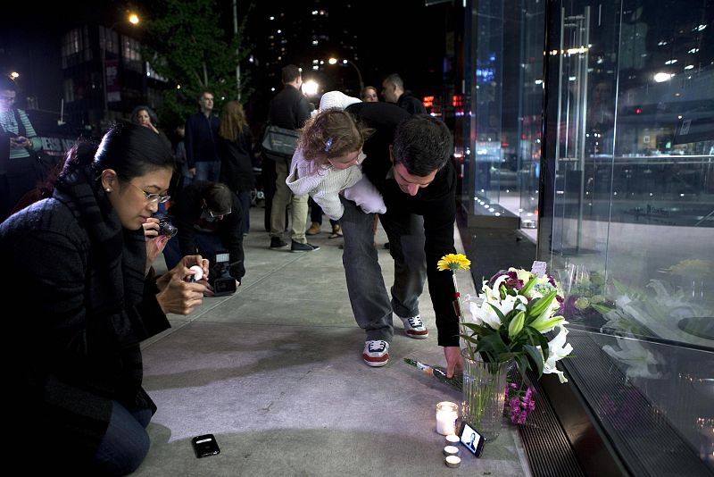 Dos personas colocan velas y flores en Nueva York.