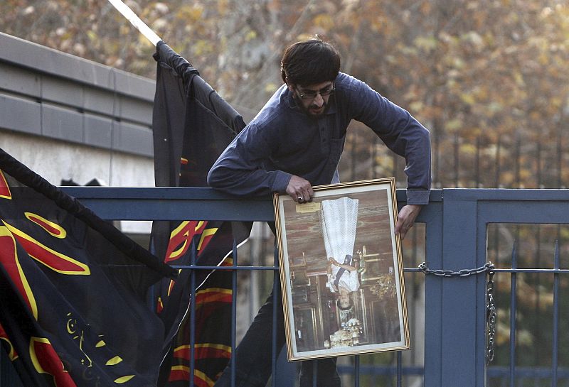 Un estudiante islámico rompe una fotografía de la reina Isabel II de Inglaterra tomada en el asalto a la embajada.