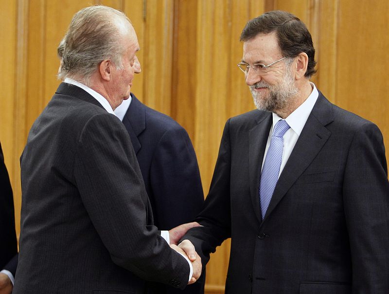 El rey Juan Carlos saluda al jefe del Ejecutivo, Mariano Rajoy (d), tras la toma de posesión de los trece ministros de su primer Gobierno, en un acto celebrado en el Palacio de la Zarzuela.