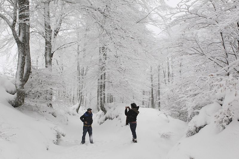 Una pareja toma fotografías en el alto de Ibañeta, en Navarra, en medio de la nieve