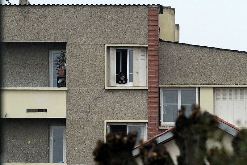 A neighbour looks at the scene during a raid on a house to arrest suspects in the killings of three children and a rabbi on Monday at a Jewish school, in Toulouse