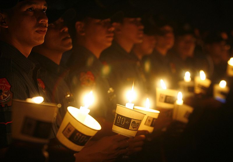 Philippine police hold candles as they join the celebration of Earth Hour in Manila's Makati financial district