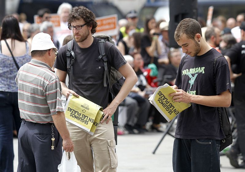 Miembros del movimiento "acampadasol" reparten periódicos del 15M en la madrileña Puerta del Sol.