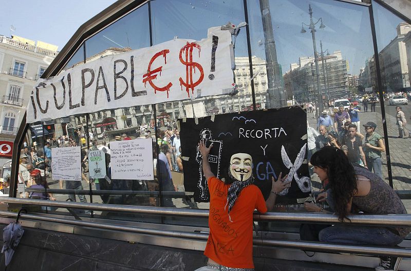 Un manifestante cuelga una pancarta en Sol