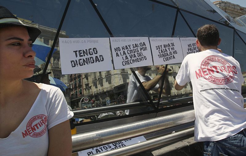 Un "indignado" pega varios carteles en la Puerta de Sol.
