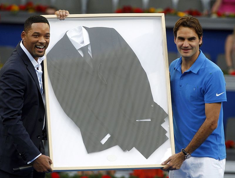 Federer of Switzerland and Will Smith pose with a suit Smith wore in the movie "Men in Black 3" and he gave to Federer after he won the Madrid Open final tennis match in Madrid