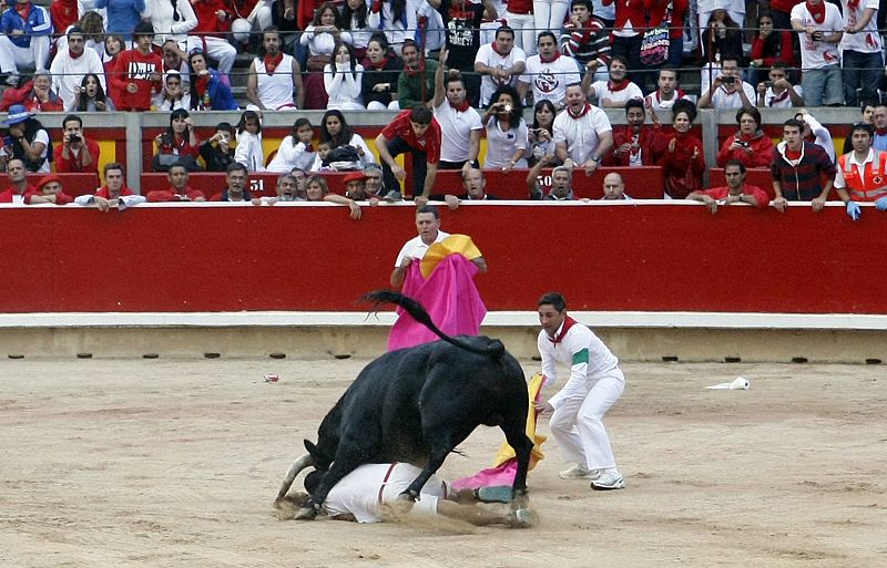 A runner gets knocked down by a Torrehandilla fighting bull at the bullring during the final running of the bulls at the San Fermin festival in Pamplona