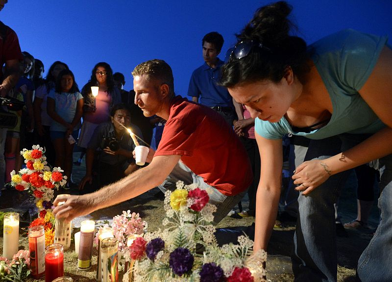 Konye places candles with other mourners during a vigil for victims behind a theater where a gunman open fire in Aurora, Colorado