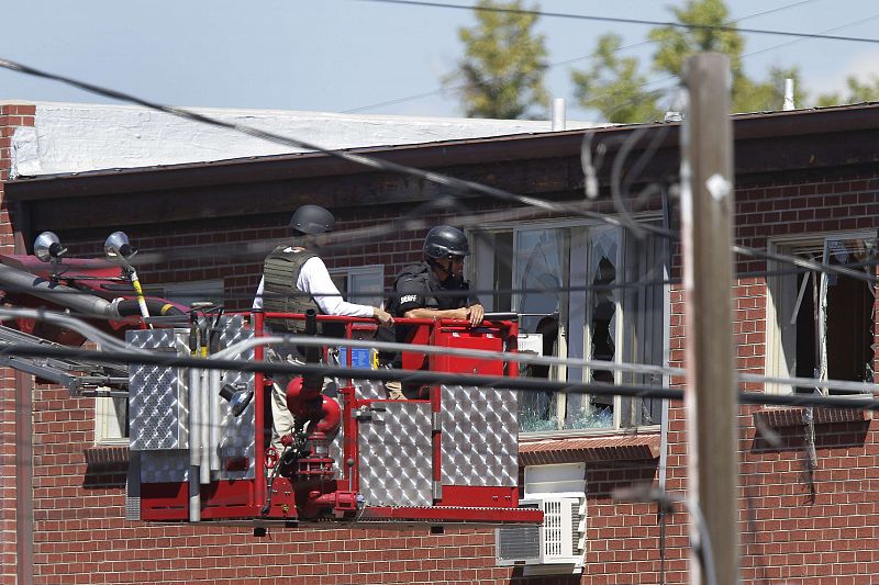 Law enforcement officers use a fire truck lift to inspect the apartment where suspect James Eagan Holmes lived in Aurora