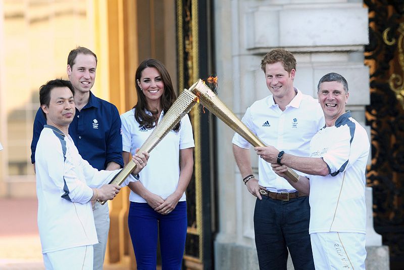 El duque  y la duquesa de Cambridge  y el príncipe Enrique observan el relevo de la antorcha olímpica de Londres 2012 entre Wai-Ming  y John Hulse en el palacio de Buckingham en Londres (Reino Unido).