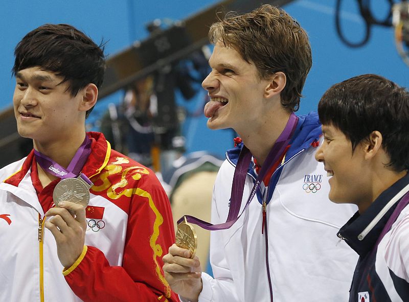 El francés Yannick Agnel, oro en 200 metros libres de natación, escoltado en el podio por el chino Yang Sun (izquierda) y el coreano Taehwan Park (derecha), que han compartido la plata.
