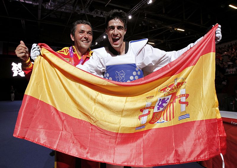 Spain's Joel Gonzalez Bonilla and his coach Francisco Martin Varela celebrate with a national flag after winning his men's -58kg gold medal taekwondo match against South Korea's Lee Dae-hoon during the London 2012 Olympic Games at the ExCeL arena