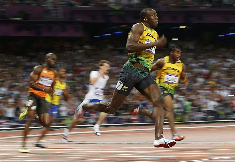 Bolt toma la curva de la carrera, seguido por Blake.